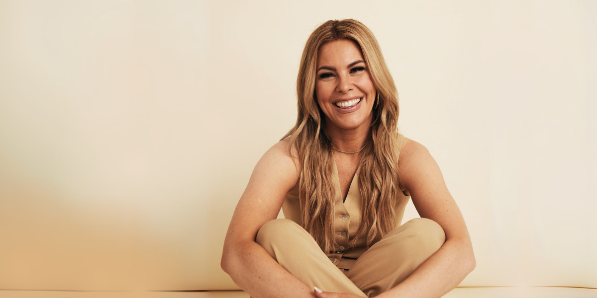 Tasha Layton wearing a tan tank top and pants with a tan background